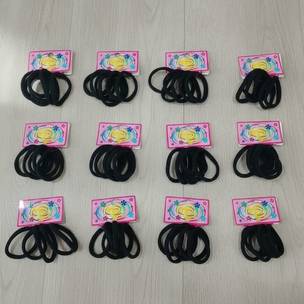 Set de tarjetas con colitas de pelo elásticas negras organizadas sobre una superficie clara.