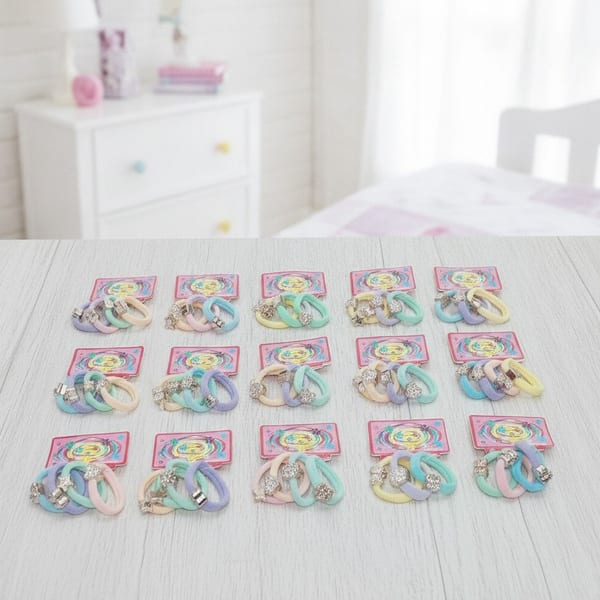 Tarjetas exhibidoras con colitas para el pelo elastizadas en tonos pastel y dijes metalizados con brillo.