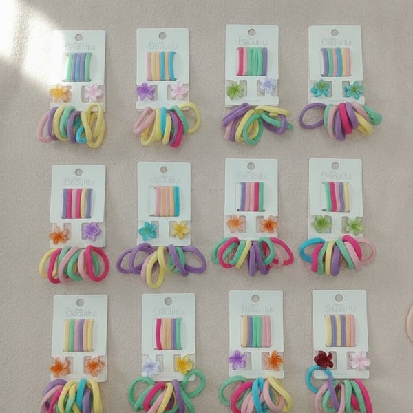 Lote de 12 tarjetas exhibidoras con colitas elásticas multicolores para el pelo y dijes de flores.