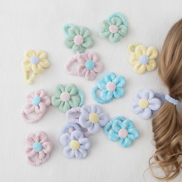 Variedad de colitas para el pelo con forma de flor de tela acolchada en colores pastel.