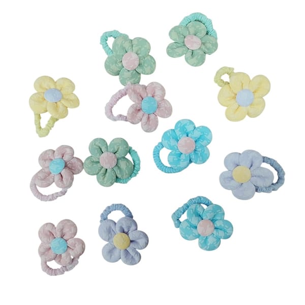 Variedad de colitas para el pelo con forma de flor de tela acolchada en colores pastel.