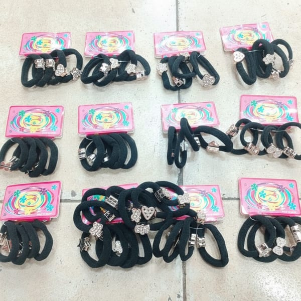 Colitas de pelo negras con dijes metálicos presentadas en tarjetas
