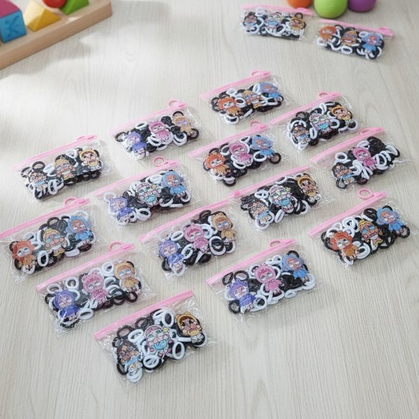 Bolsitas transparentes con cierre rosa llenas de colitas elásticas para el pelo en blanco y negro con estampado de personajes infantiles