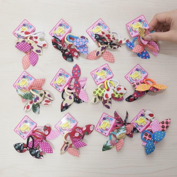 Tarjetas exhibidoras con colitas para el pelo con orejitas de tela en colores y diseños surtidos.