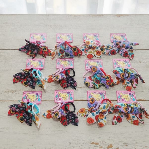 Tarjetas exhibidoras con colitas para el pelo con lazos estampados de flores surtidas