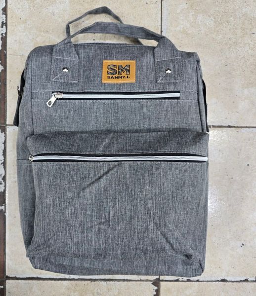 Mochila urbana de tela gris melange con bolsillos frontales y manijas superiores