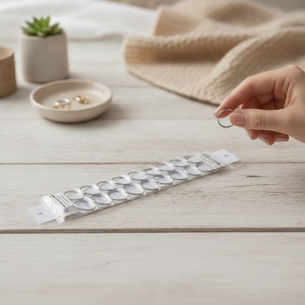 Tira exhibidora transparente con doce pares de aritos argollitas plateadas
