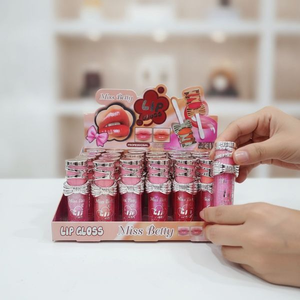 Caja exhibidora con 24 unidades de brillo labial marca Miss Betty con tapas decorativas metálicas
