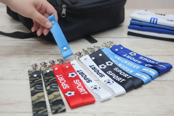Llaveros de cinta textil surtidos con mosquetón metálico, estampados deportivos, camuflado y bandera de Argentina.