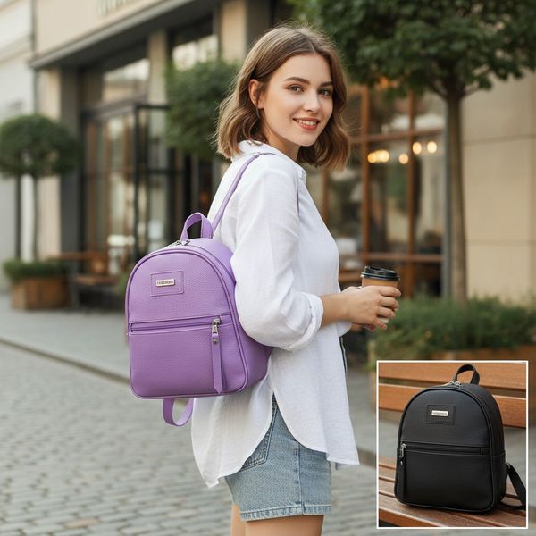 Dos mochilas mini de eco cuero, una de color violeta y otra negra, con bolsillo frontal y plaqueta metálica.