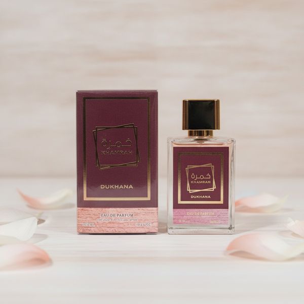 Frasco de perfume Khamrah Dukhana con tapa dorada junto a su caja de presentación borravino y dorada