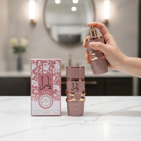 Frasco de perfume Lattafa Yara Elixir rosa con detalles dorados al lado de su caja de presentación.