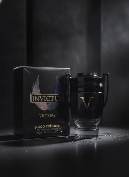 Perfume masculino Invictus Victory en frasco negro con forma de trofeo junto a su caja