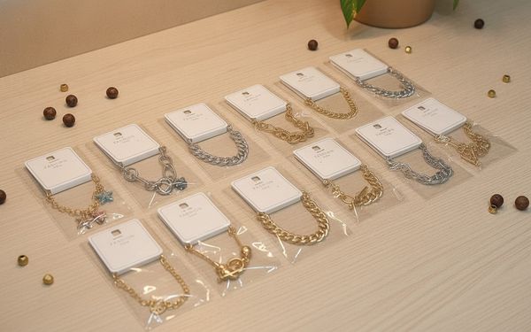 Variedad de pulseras de cadena y bijouterie en empaques individuales con tarjeta.