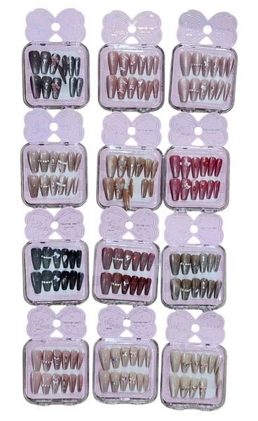 Cajas de uñas postizas decoradas en tonos rosa, nude y negro con brillos y apliques