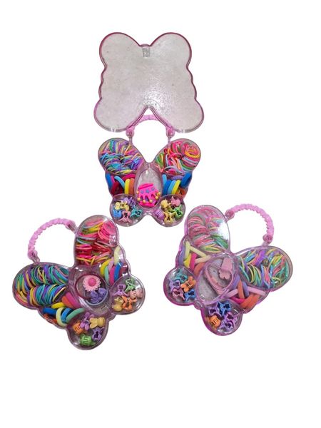 Valijita plástica transparente con forma de mariposa conteniendo colitas y mini broches multicolores para el pelo.