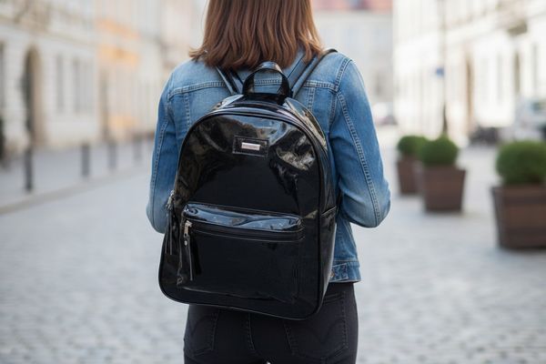 Mochilas urbanas para mujer confeccionadas en charol negro con bolsillo frontal