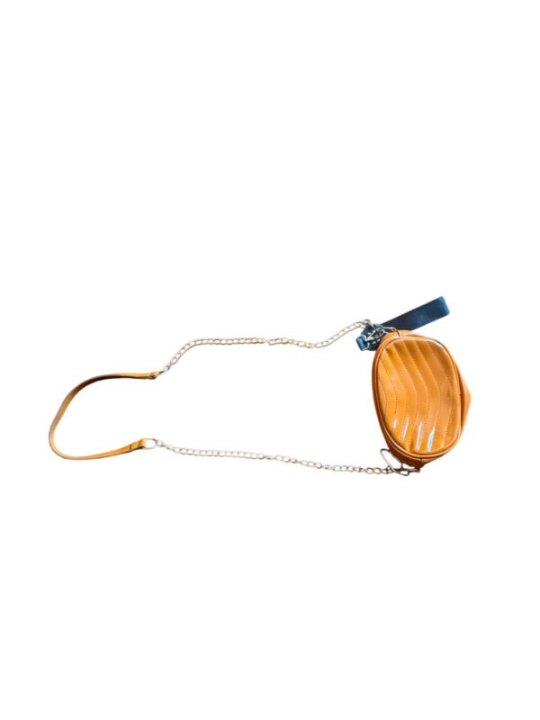 modacool-bandolera-ovalada-mostaza-cadena-fondo-blanco.jpg Bandolera pequeña color mostaza con correa de cadena sobre superficie de madera